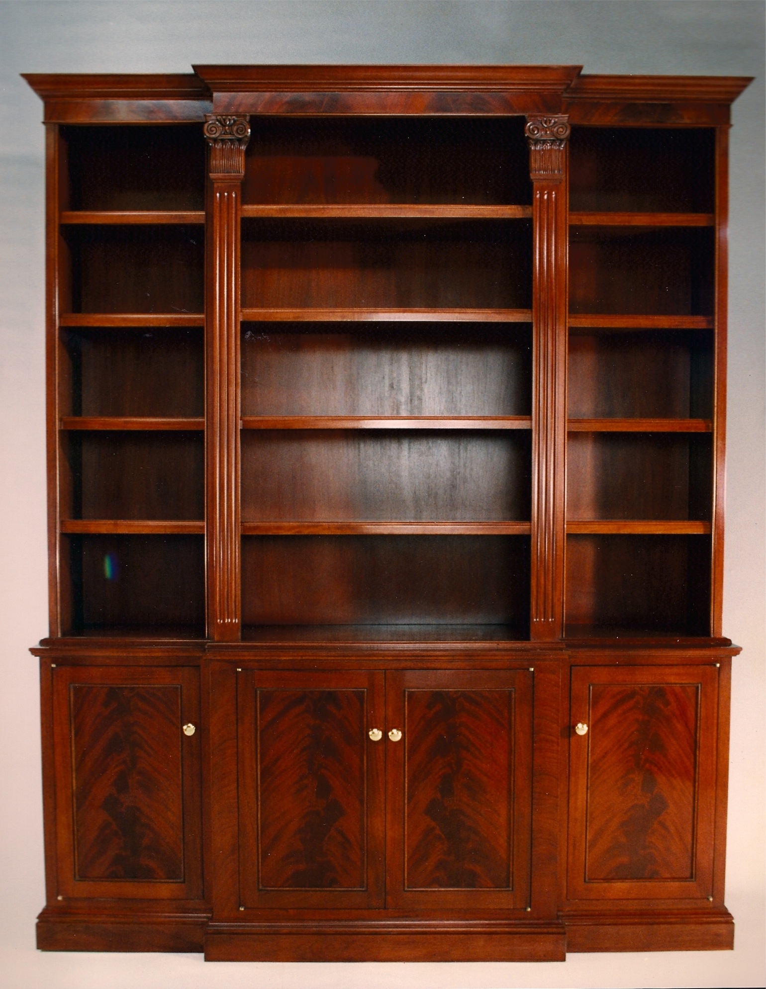 Traditional mahogany breakfront bookcase with hand-carved capitals and crotch veneer work.