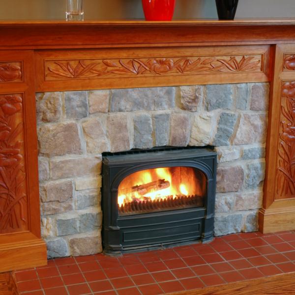 Solid cherry fireplace surround in an Arts and Crafts style embellished with hand carved lily motif.
